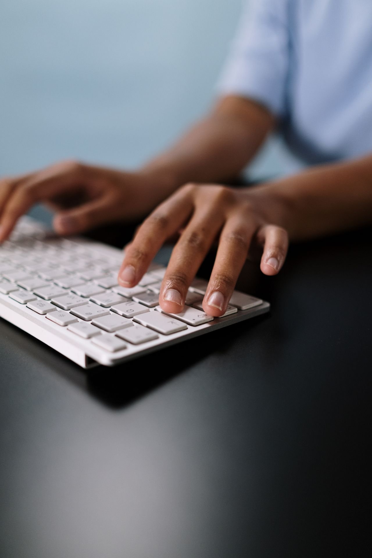 Hands typing on a white keyboard